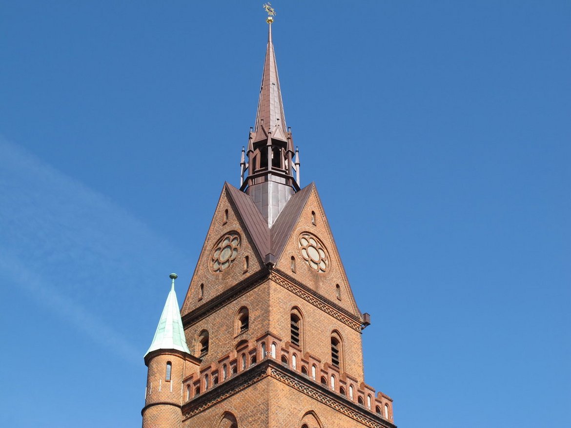 Die Turmspitze der Herz-Jesu-Kirche ragt in den blauen Himmel